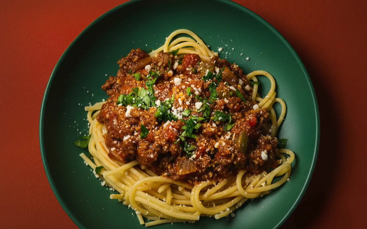 A plate of spaghetti with saigon sunday bolognese meat sauce garnished with fresh herbs and grated cheese.
