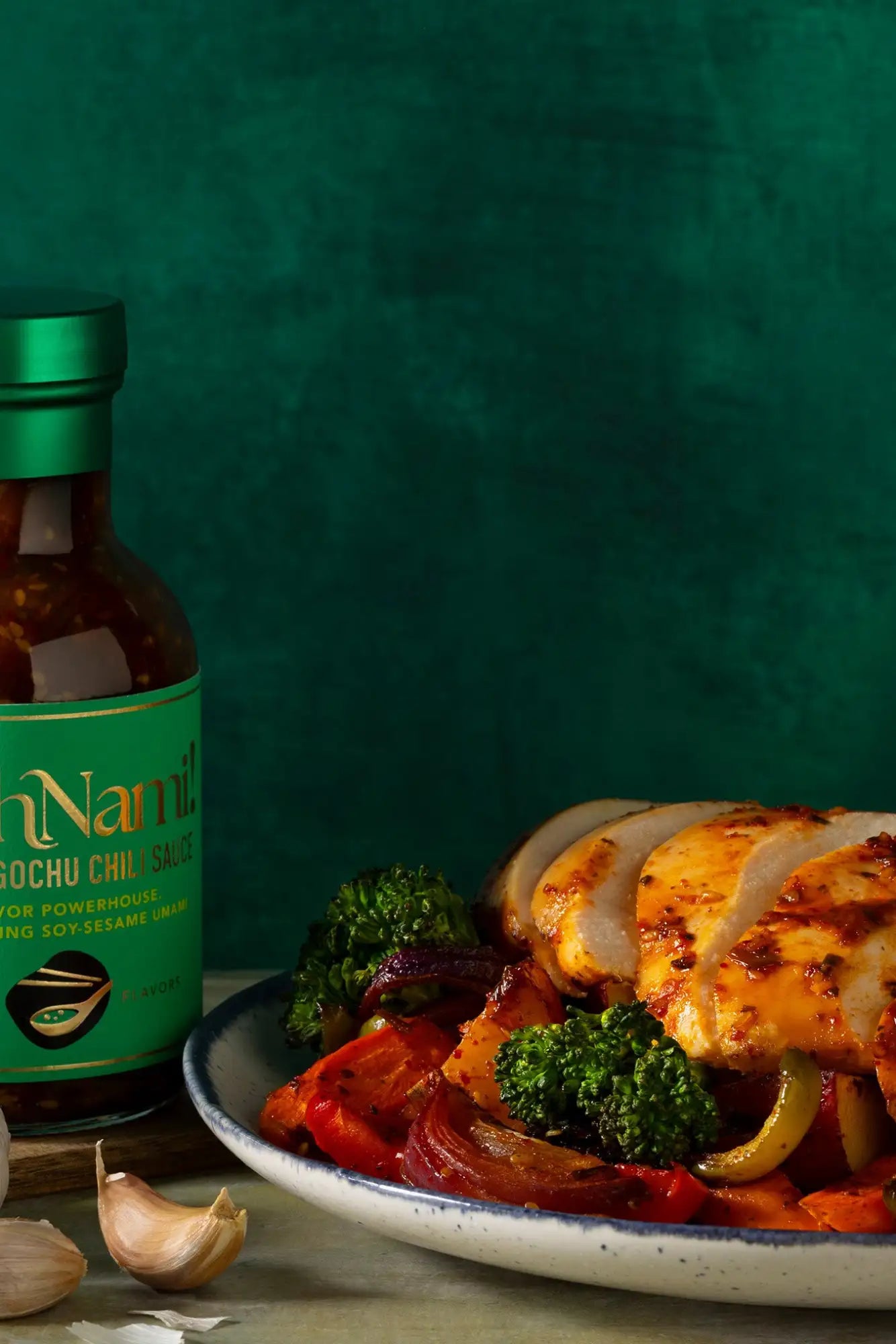 A bottle of namilk gochu chili sauce with a green label and metallic green cap, containing a dark red sauce.