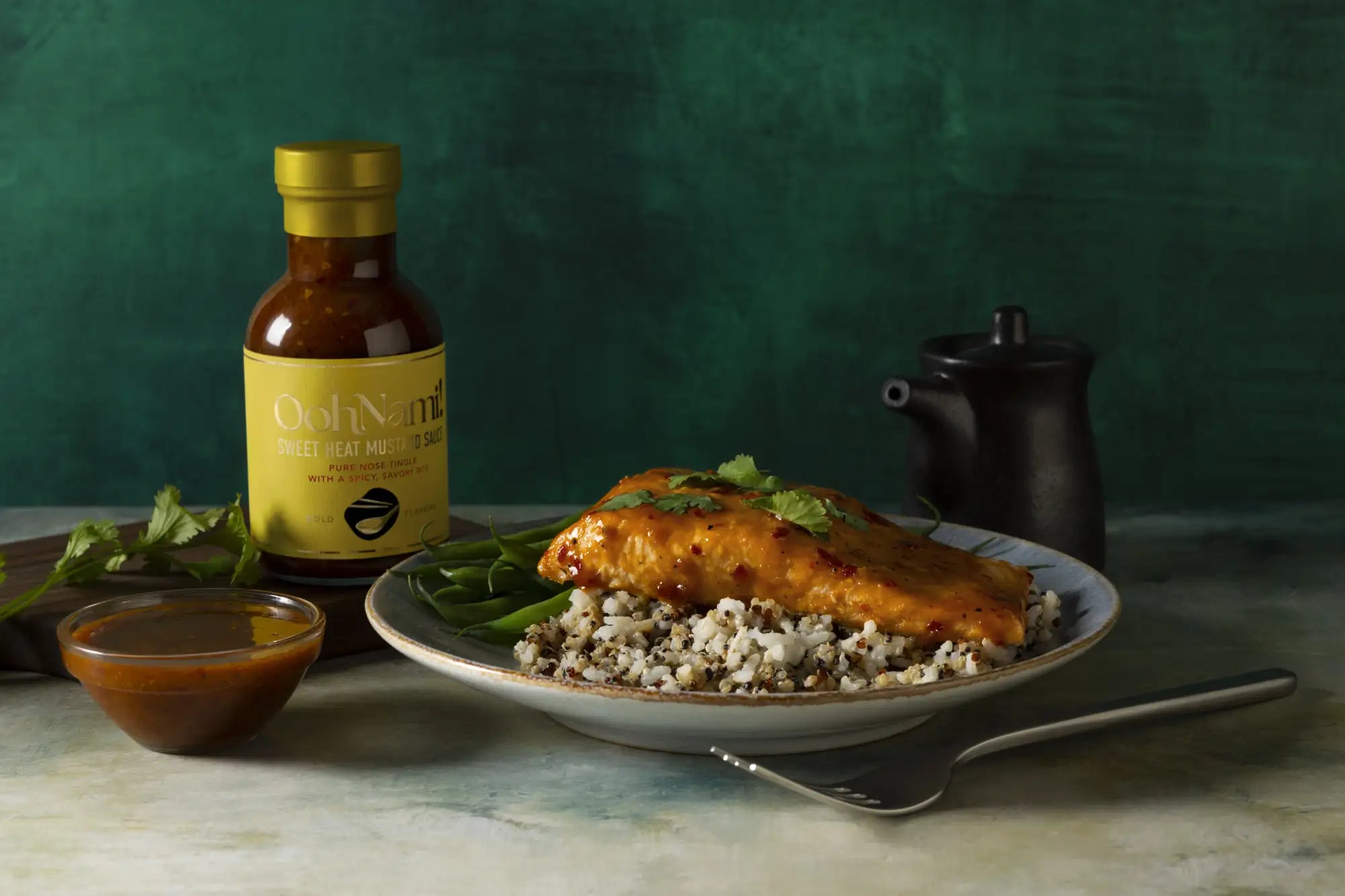 A bottle of oohnami sweet heat mustard sauce with a golden lid and yellow label, containing amber-colored sauce.
