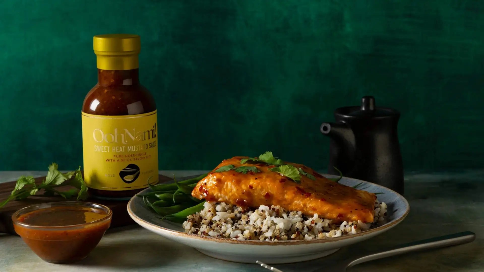 A bottle of oud nami sweet heat mustard sauce with a yellow label and gold cap, containing a reddish-brown sauce.