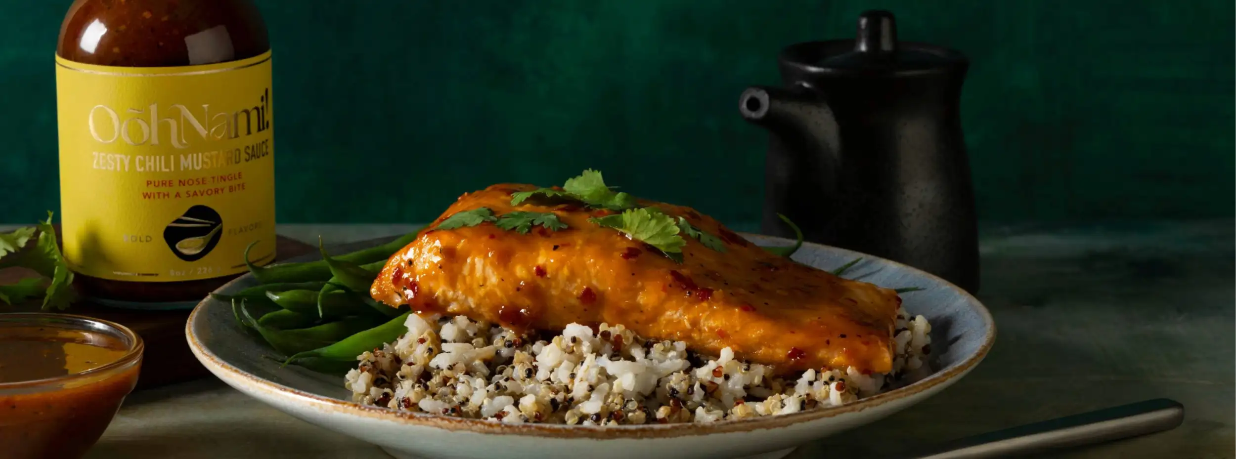 A vibrant orange glazed salmon fillet rests atop a bed of quinoa and green beans, garnished with fresh cilantro.
