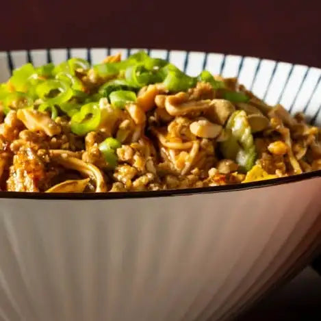 A white ceramic bowl with a black rim and vertical ridges, filled with a savory dish topped with chopped green onions.